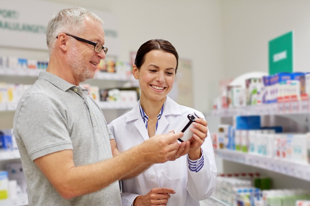 pharmacist showing drug to senior man at pharmacy