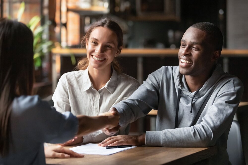 happy couple shaking hands with insurance person after signing documents