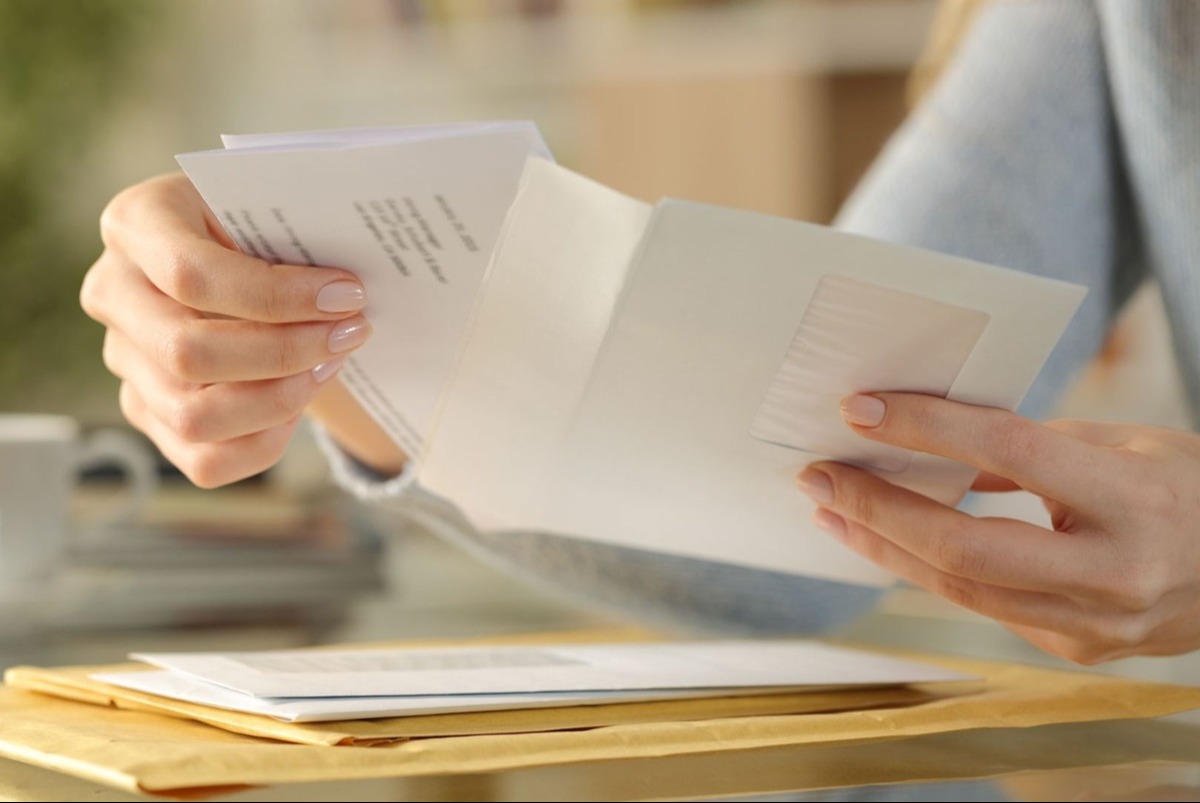 Woman's hands opening an envelope from a stack on her desk